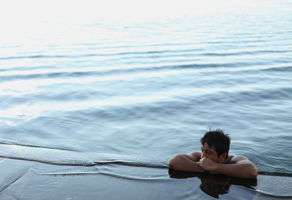 Flores Guatemala is a tiny island in the middle of Lake Peten Itza. The residents have a habit of jumping in the water at random times - swimming for just a few minutes and then going back to whatever they were doing. This gentleman went for a really long swim and is resting for a moment while his girlfriend waits on the shore. Photo: Alex Washburn
