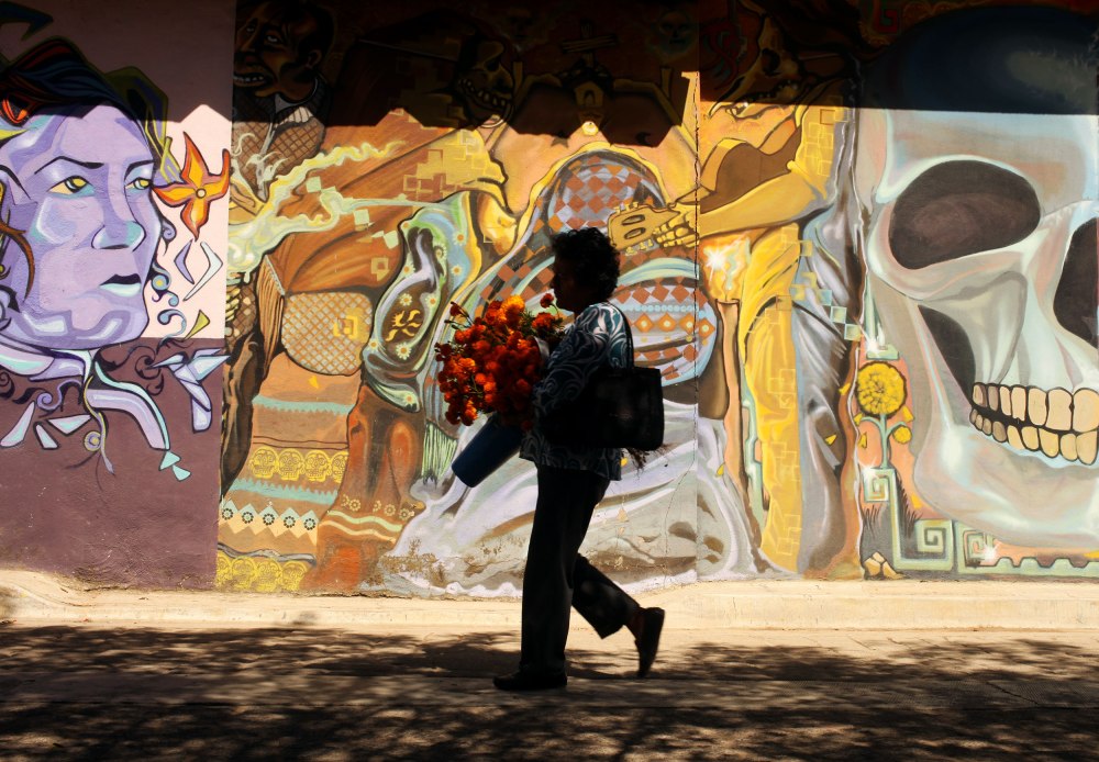 A woman carries marigolds traditionally used for Dia De Los Muertos decorations through the town of Xoxocotlan Mexico. Photo: Alex Washburn