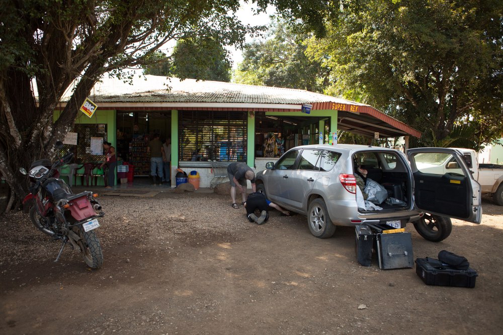 There could be a reason that the GPS told us to go around the peninsula and take a ferry to Montezuma instead of driving there from Tamarindo. On a path that is not serviceable in the rainy season, Dave in his Rav4 and we on the bikes, set out on our way to Montezuma (maybe this was a little revenge for us), along the only main highway that connects the peninsula with he mainland.  Once we got to the junction of 18 and 21, we shut the GPS off and traveled on into the green wilderness. (Here Dave and Nathaniel are fixing Dave's flat tire) Photo: Alex Washburn