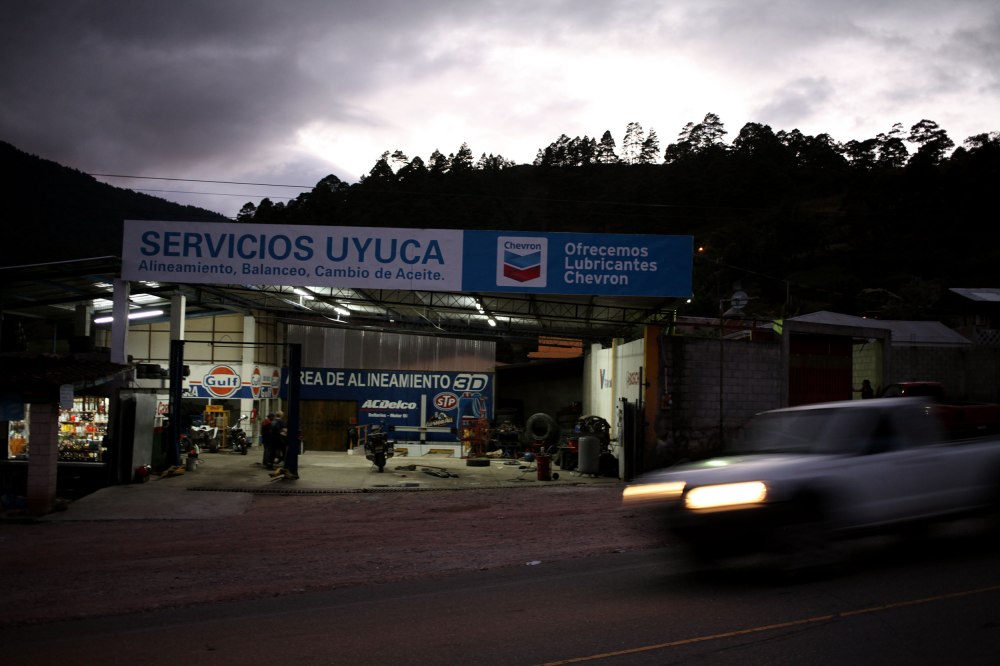 Storm clouds approach as two mechanics in a town we don't know the name of struggle to get both our bikes back on the road. Photo: Alex Washburn