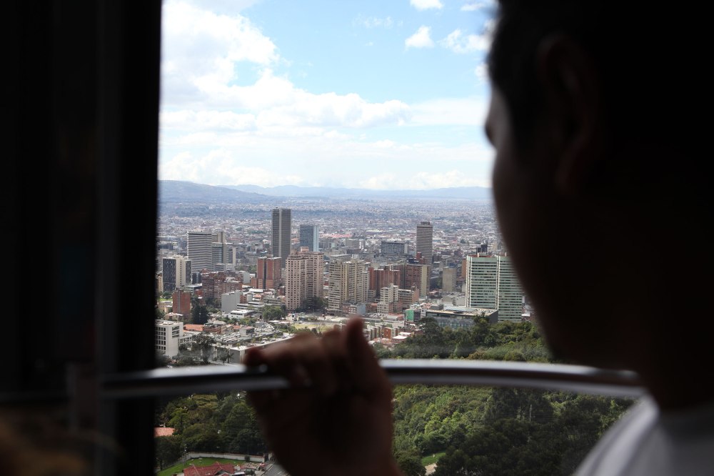 A man looks out over Bogota Colombia from the Transferico cable car that gives tourists and locals a view of the city from the top of a nearby mountain. Photo: Alex Washburn