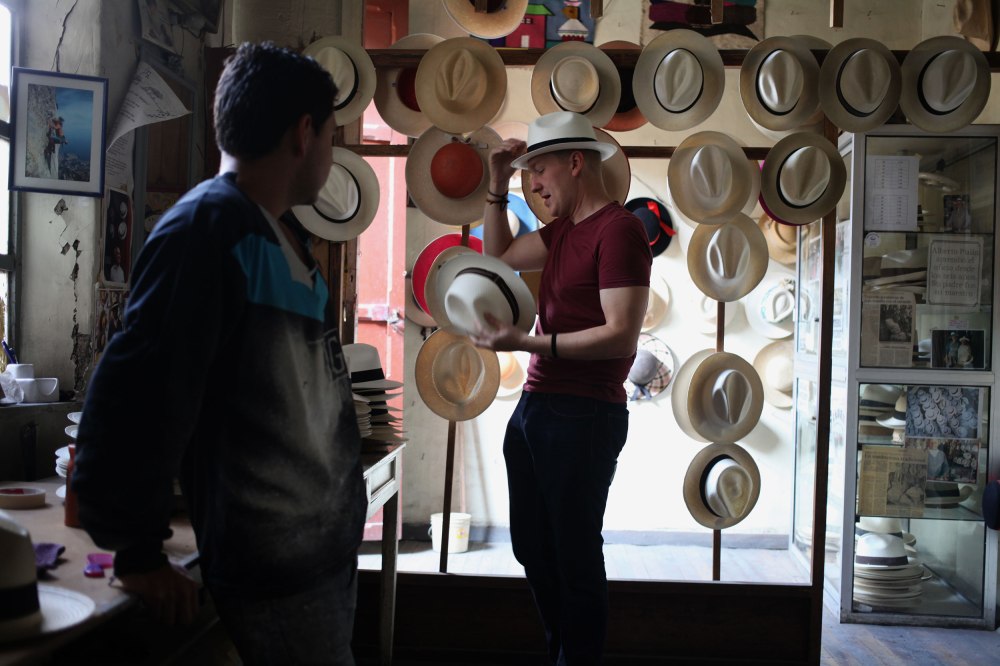 Nathaniel tries on hats trying to determine which one fits best as Juan-Carlos watches and answers questions. Photo: Alex Washburn